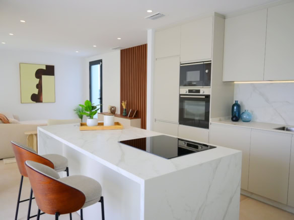 Ruime, lichte keuken met marmeren werkblad, vier stoelen en decoratieve glazen vazen.
