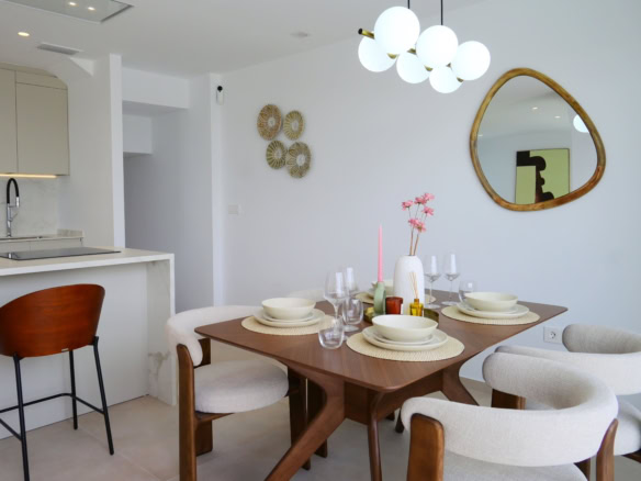 Licht interieur met moderne eetkamertafel en designstoelen, open keuken met witte kasten en marmeren werkblad.