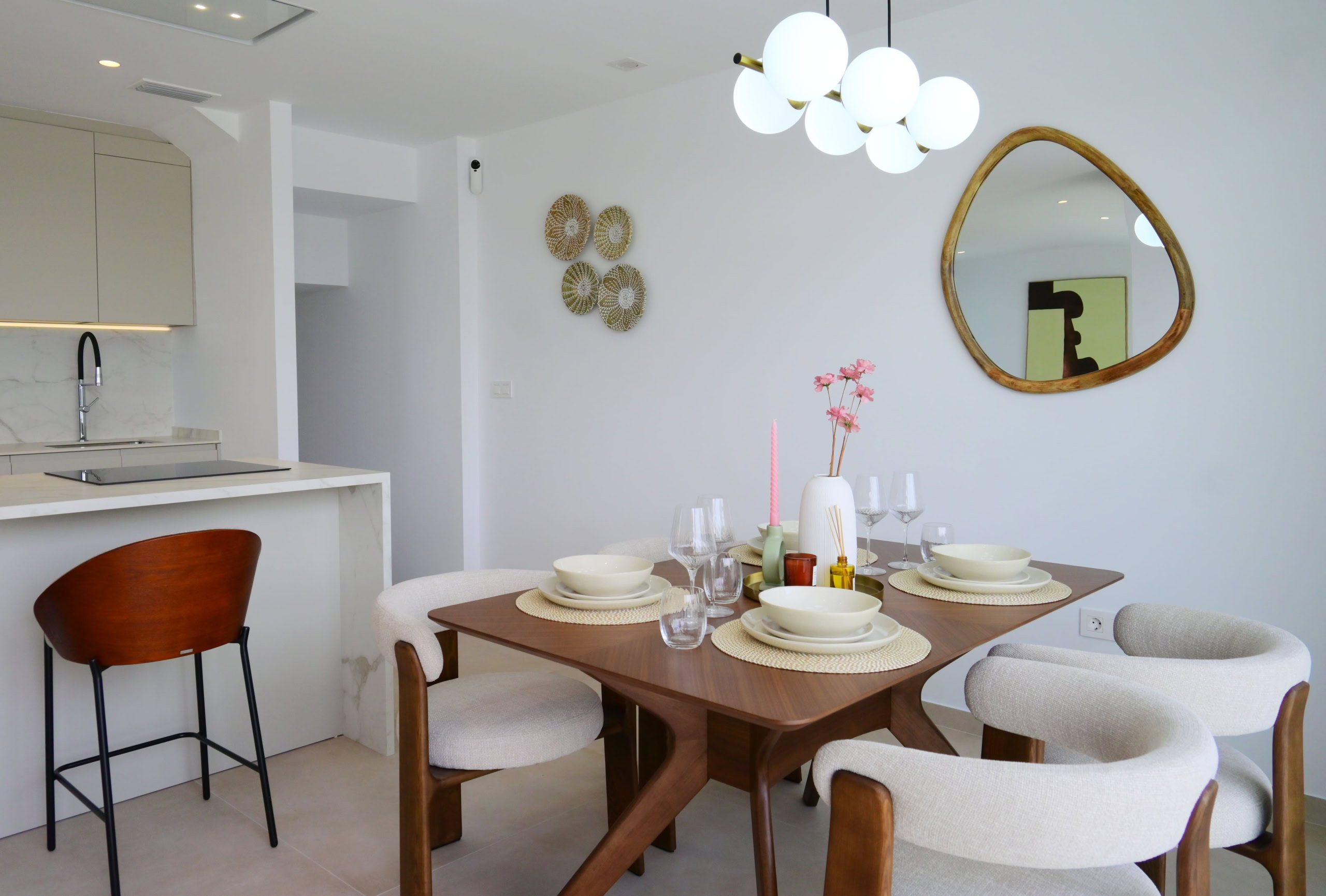 Licht interieur met moderne eetkamertafel en designstoelen, open keuken met witte kasten en marmeren werkblad.
