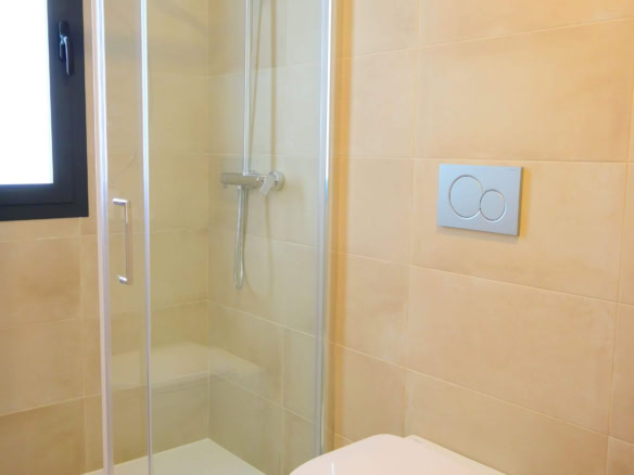 Lichte badkamer met inloopdouche, modern toilet en raampje voor frisse lucht en daglicht.