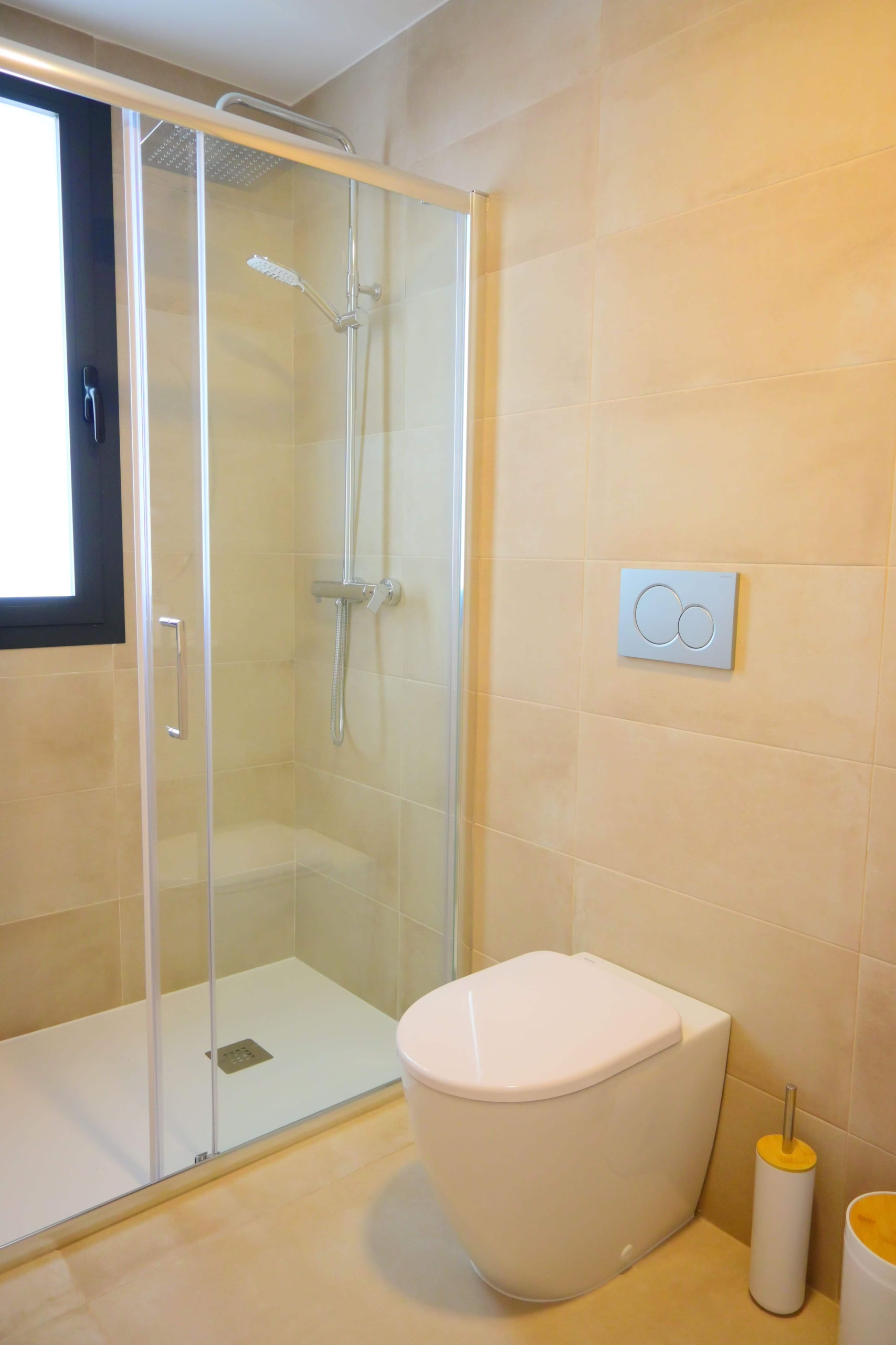 Lichte badkamer met inloopdouche, modern toilet en raampje voor frisse lucht en daglicht.