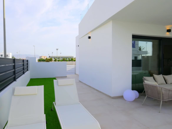 Ruime dakterras met wit lounge meubel, kunstgras en sfeerlicht, perfect voor genieten in de buitenlucht.
