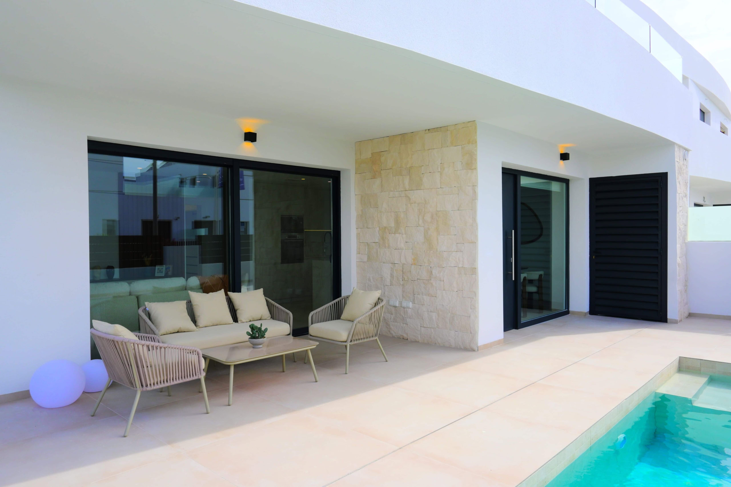 Luxe terras met zwembad en zitje, modern appartement met grote glazen deuren.