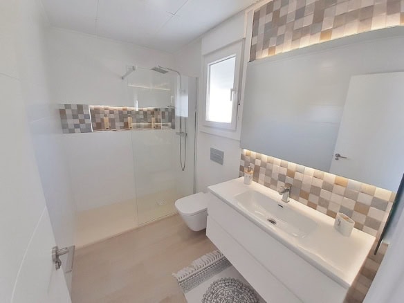 Ruime badkamer met inloopdouche en wandspiegel.
