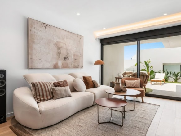 Ruime woonkamer met comfortabele bank, decoratieve kussens en natuurlijke lichtinval.
