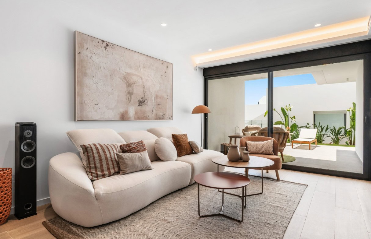Ruime woonkamer met comfortabele bank, decoratieve kussens en natuurlijke lichtinval.