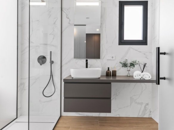 Moderne badkamer met marmeren wanden, inloopdouche en wastafel in Cumbre del Sol.