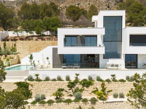 Moderne luxe villa in Altea met grote ramen, zwembad en prachtig uitzicht op de omgeving.
