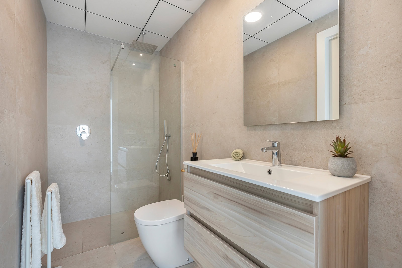 Modern badkamer met strakke inrichting en natuurlijke tinten Moderne badkamer met inloopdouche, toilet en wastafel in een nieuwbouwappartement.