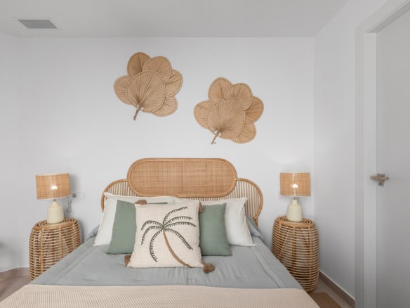 Zonnetje in Huis Makelaardij: Ibiza-stijl slaapkamer met rieten decoratie en natuurlijke kleuren.
