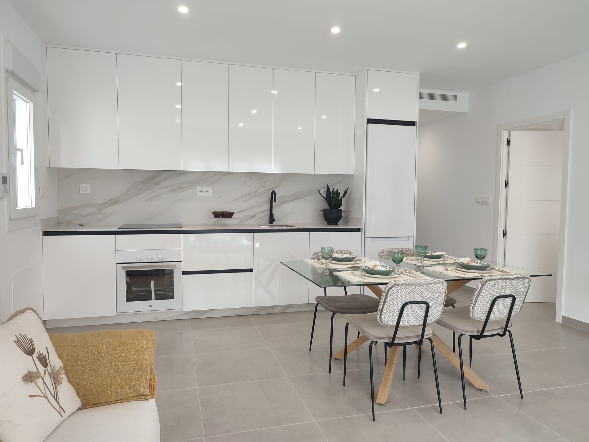 Moderne witte keuken en eethoek in nieuwbouw villa Moderne witte keuken met ingebouwde oven en vaatwasser, eethoek met vier stoelen in een nieuwe villa.