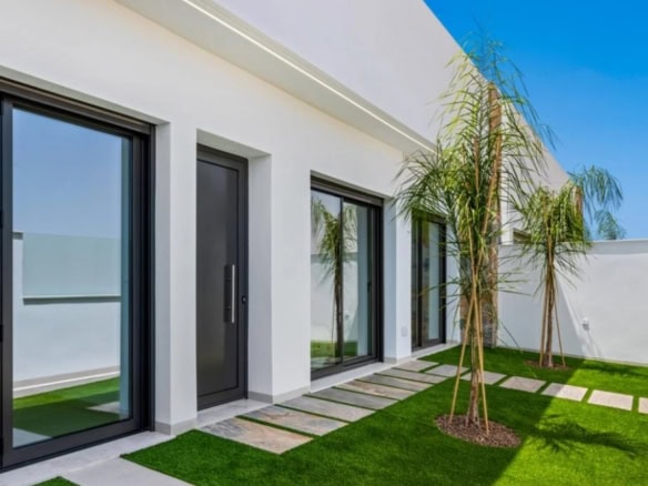 Villa met grote glazen schuifdeuren en tuin met palmboom.