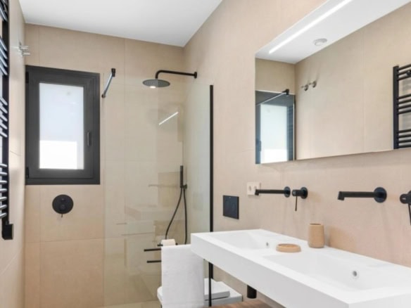Moderne badkamer met inloopdouche, grote spiegel en zwart accenten.
